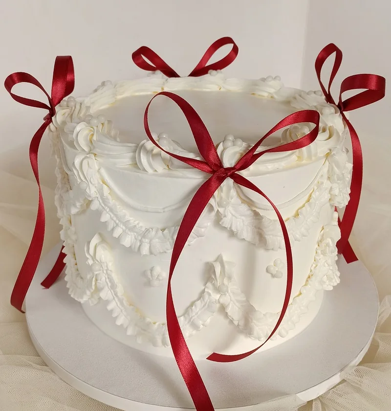 Torta di laurea in stile Lambeth decorata con fiocchi di raso rossi